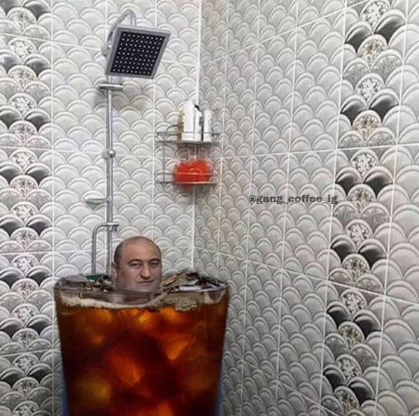 A cursed coffee meme of a man bathing in a giant glass of iced coffee in a shower.