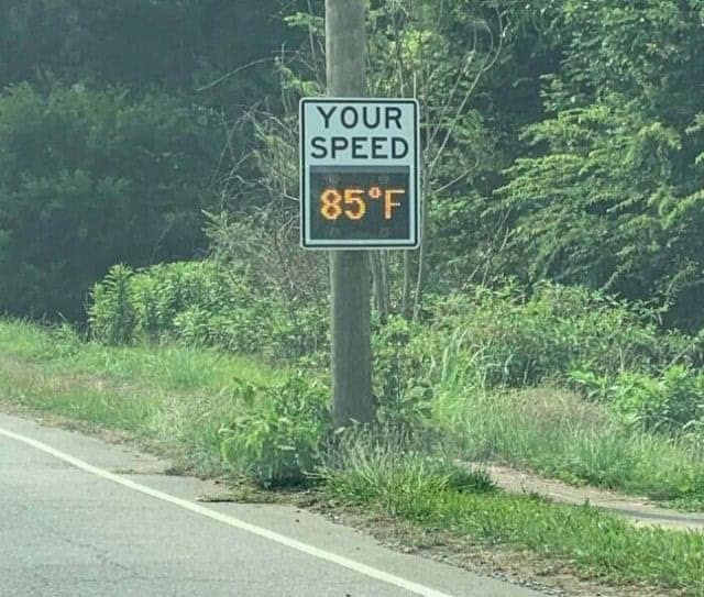 A roadside digital speed radar sign that has malfunctioned and is incorrectly displaying the current outdoor temperature in Fahrenheit (85°F).