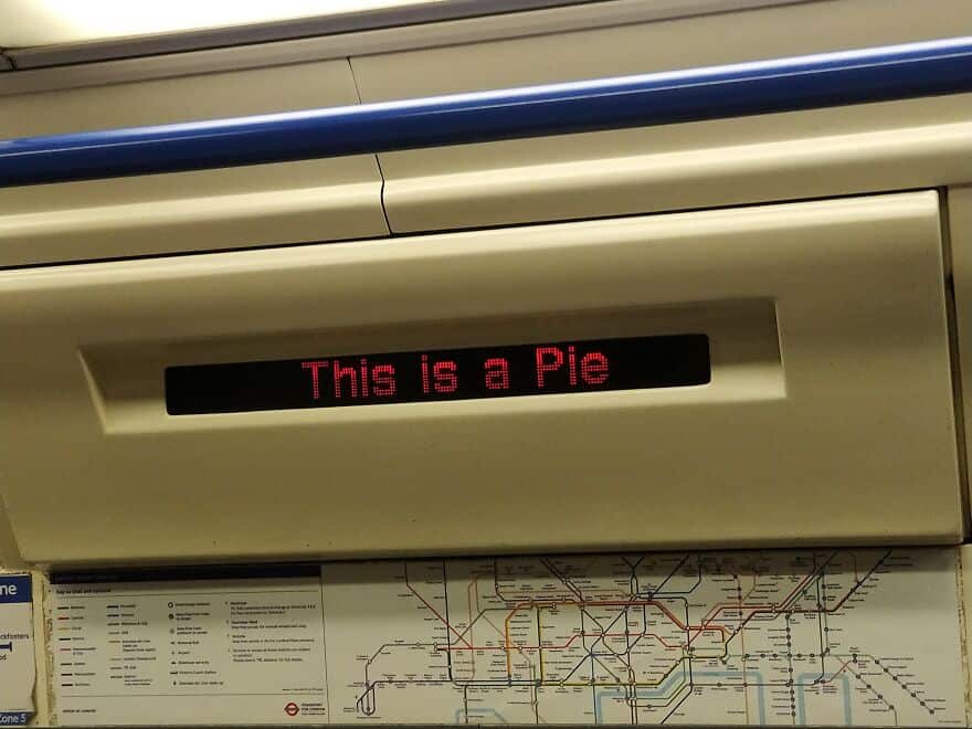 The digital information screen on a subway or train car has a major glitch and is displaying the random and surreal phrase "This is a Pie."