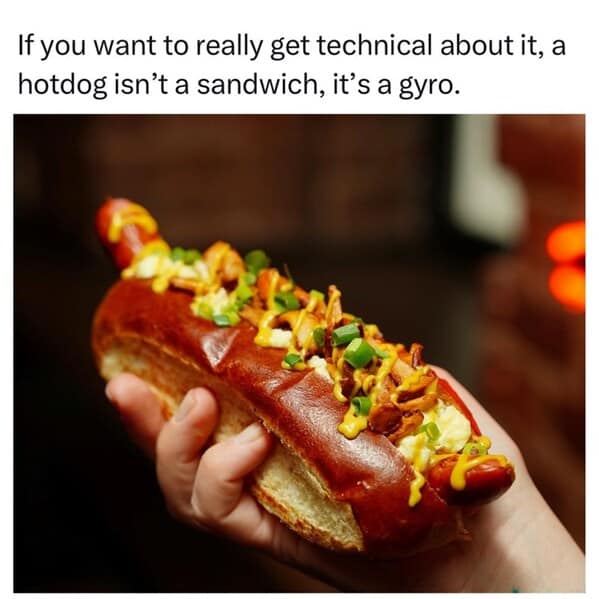 Close-up of a loaded hot dog in a pretzel bun; caption debates sandwich status.