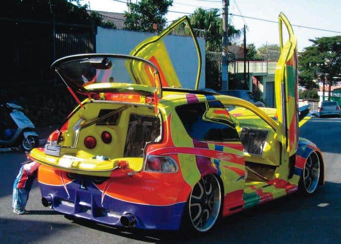 A cursed image of a heavily modified and colorful hatchback car from the early 2000s.