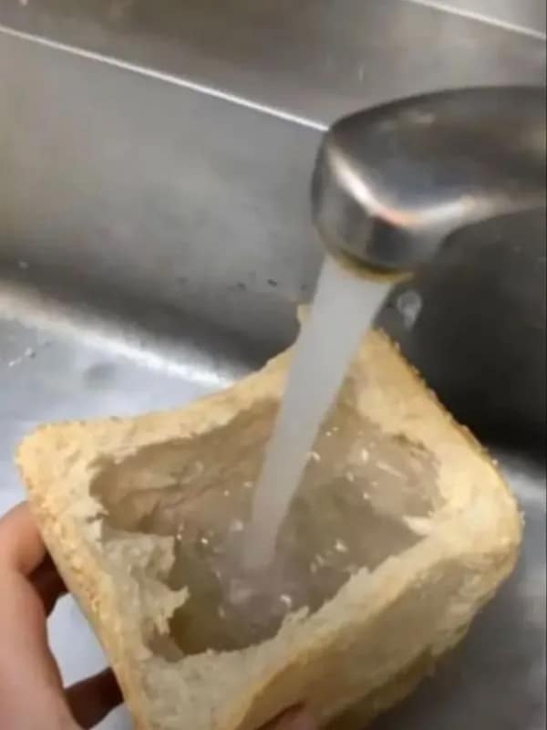 A cursed image of someone filling a hollowed-out loaf of bread with tap water.