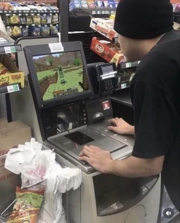 A cursed image of a person playing the video game Minecraft on a grocery store self-checkout machine.