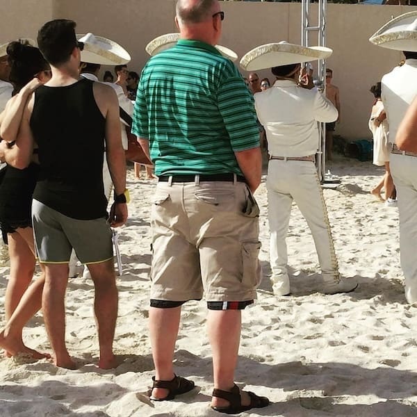 A great dad fit for the beach, including a tucked-in striped polo shirt and belted khaki cargo shorts.