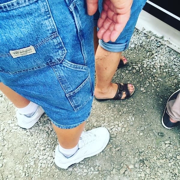 A powerful dad fit featuring long denim Wrangler shorts, also known as jorts, with white athletic sneakers.
