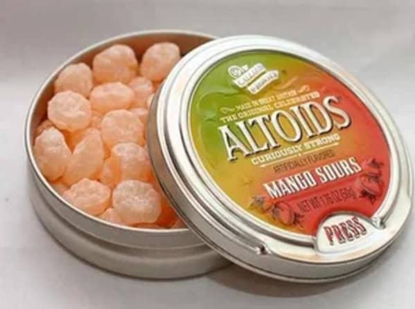An open silver tin of the intensely sour and much-missed discontinued candy, Altoids Mango Sours from the 2000s.v