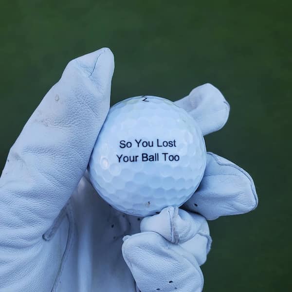 A funny and very empathetic found golf ball with the message "So You Lost Your Ball Too" printed on it.