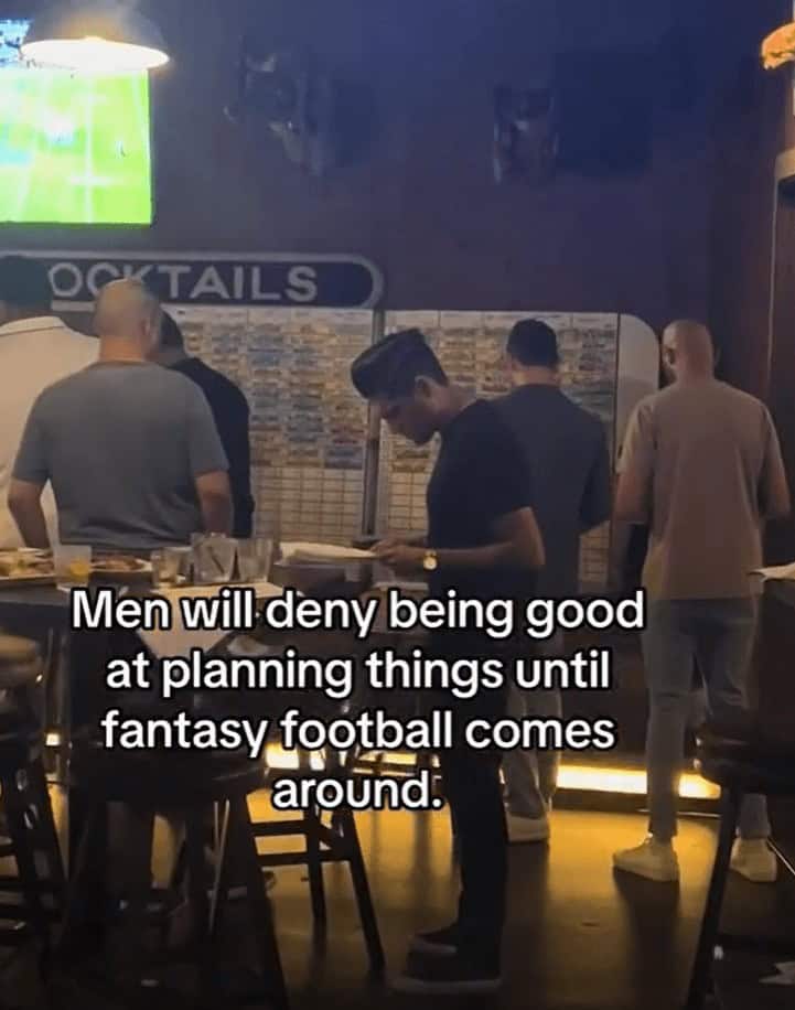 Men studying a huge draft board in a bar with text about suddenly being good at planning for fantasy football.