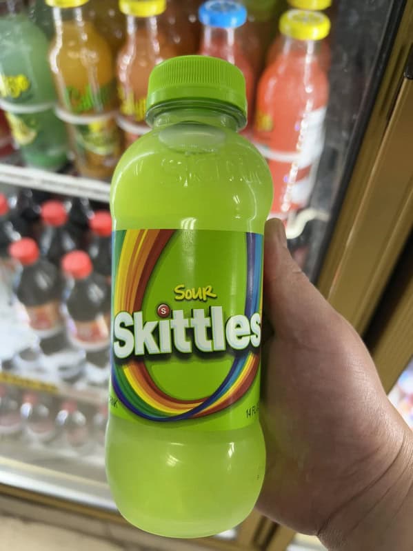 A bottle of a bizarre, bright green drink from a convenience store that is flavored like sour Skittles candy.