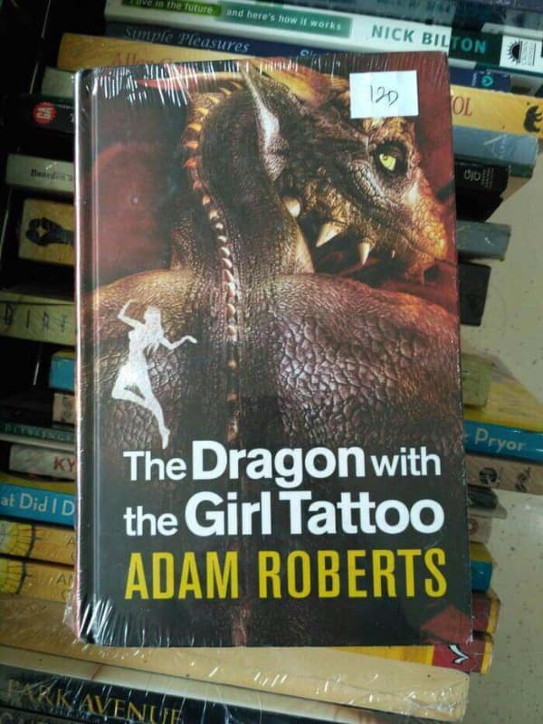 A hilarious parody fantasy book titled "The Dragon with the Girl Tattoo," which is a clear and funny knock-off of the famous thriller novel.