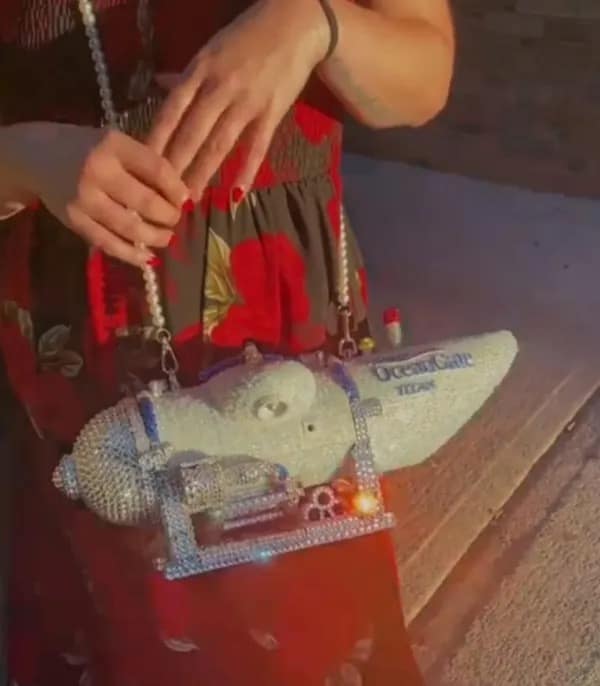 A shocking photo of a woman holding a bizarre, custom-made purse that is a bedazzled, rhinestone-covered replica of the OceanGate Titan submersible.