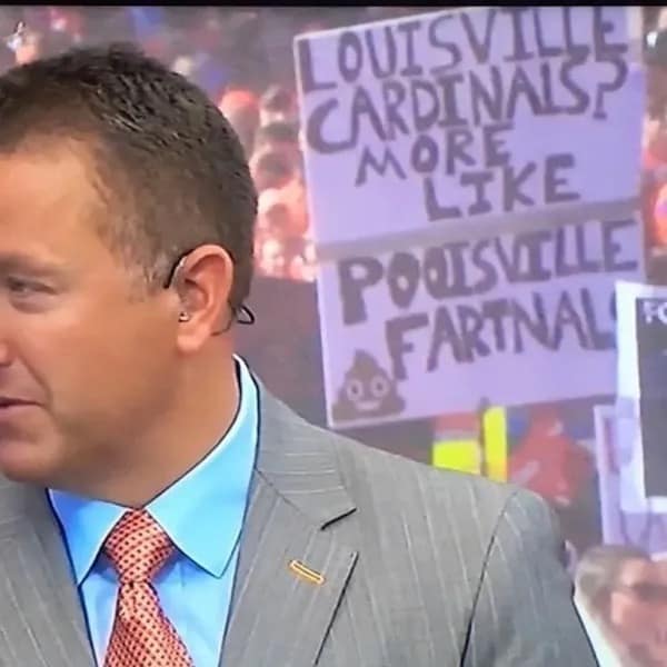A sports fan in the crowd holds a sign with a childishly insulting rhyme for the Louisville Cardinals.