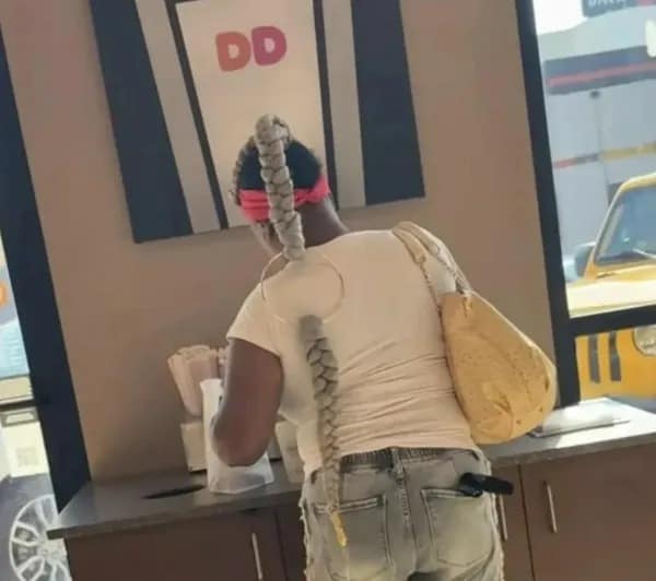 A photo of a woman with a long, thick braid uniquely styled through a large ring on her shirt.