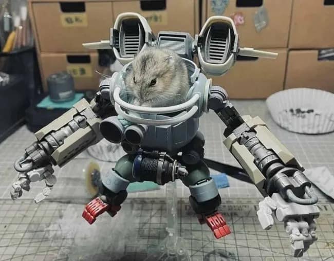 An amazing and slightly terrifying photo of a tiny and very cute pet hamster who is sitting inside of a very large and custom-built, Gundam-style robot mech suit.