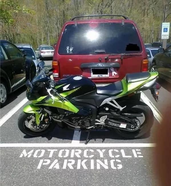 A very satisfying photo of a bright green and black sport motorcycle parked perfectly within the lines of its designated spot.