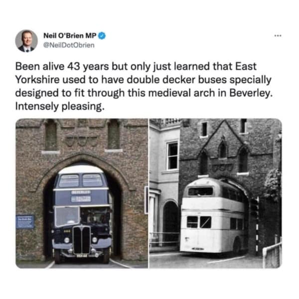 A cool picture of vintage double-decker buses designed to perfectly fit through a low medieval arch in England.