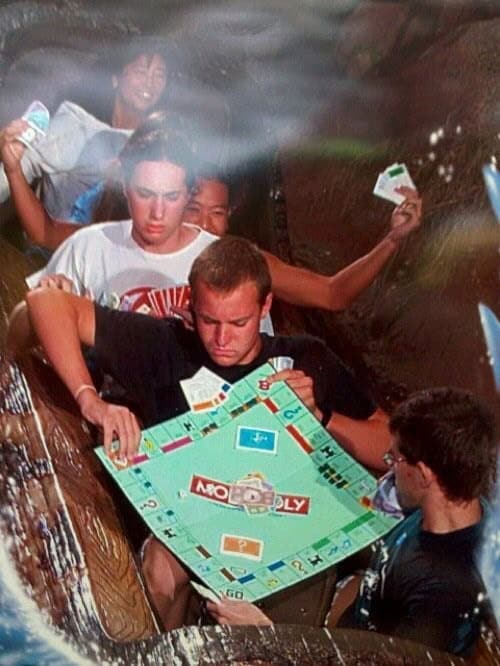 A funny rollercoaster pic of a group of friends playing a very serious game of Monopoly on Splash Mountain.