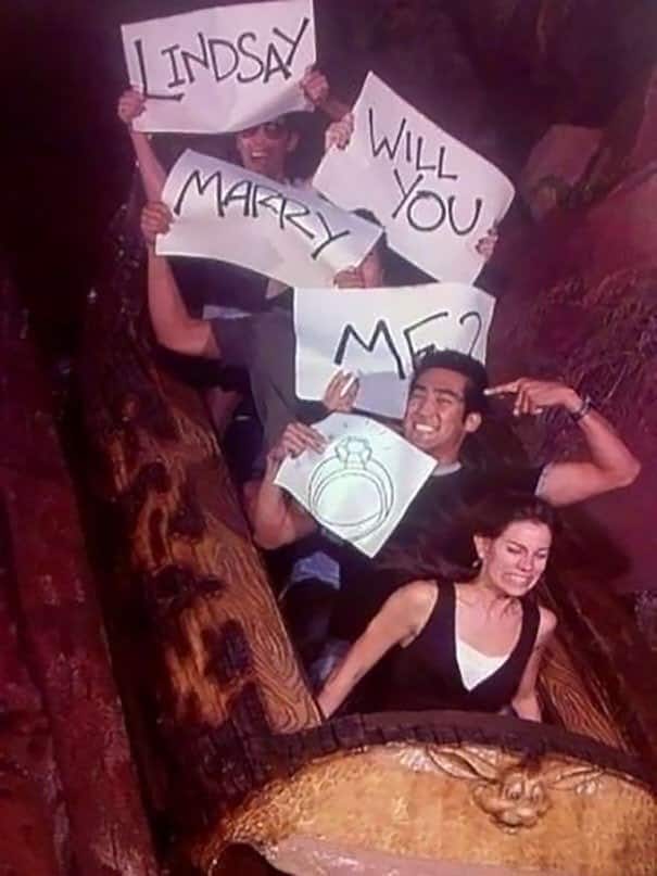 A sweet and funny rollercoaster photo of a man proposing to his terrified girlfriend with signs on Splash Mountain.