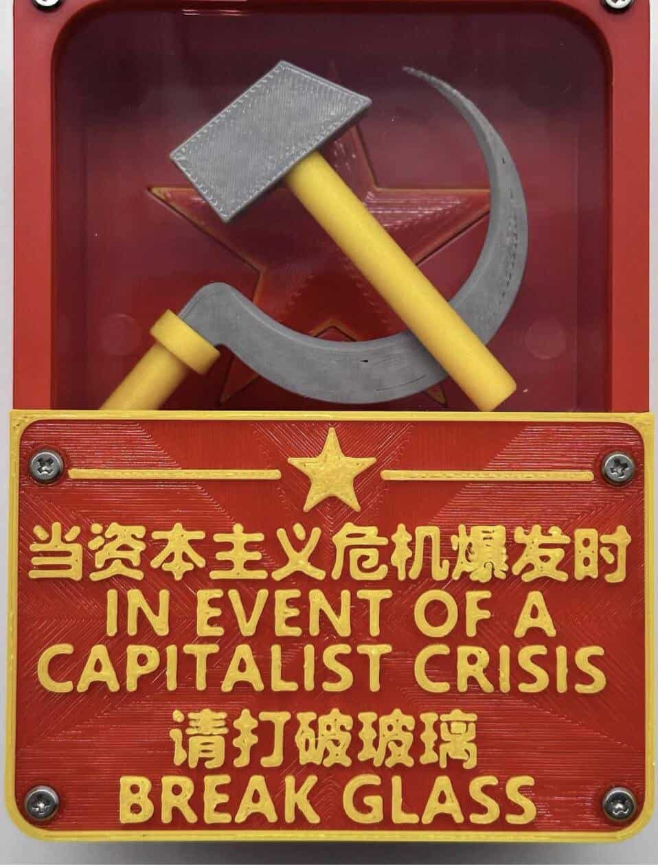 Red emergency case with hammer and sickle; text: “IN EVENT OF A CAPITALIST CRISIS BREAK GLASS,” English and Chinese