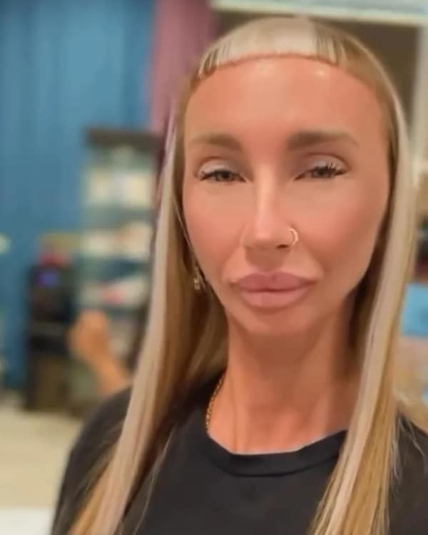 Woman with ultra-short micro bangs bleached lighter than her long straight hair, posing in a salon.