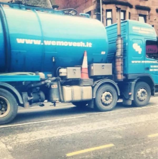 A septic tank or waste removal truck with the very clever and funny website URL "www.wemovesh.it" printed on the side.