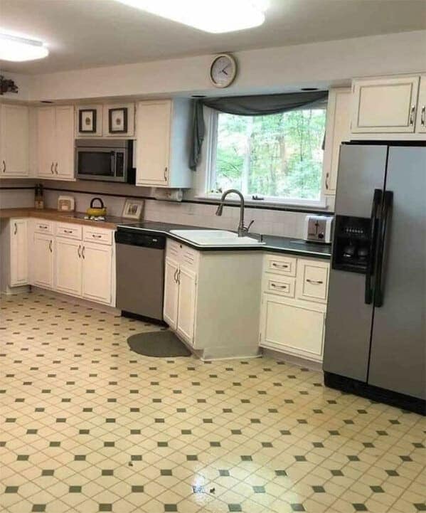 Dated kitchen with misaligned sink peninsula and random floor patch by the cabinets.
