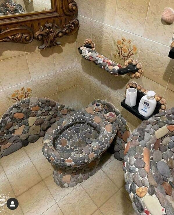 Bathroom covered in glued river stones—including the toilet, sink edge, and shelves.
