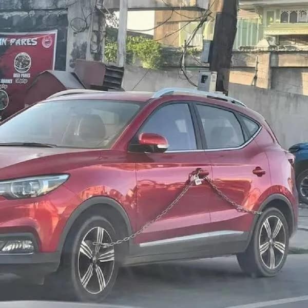 A meme dump photo of a questionable car security system using a chain and padlock.