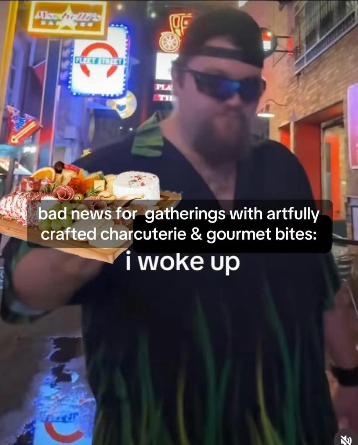 A funny meme for food lovers showing a man ready to devour a charcuterie board at a gathering.