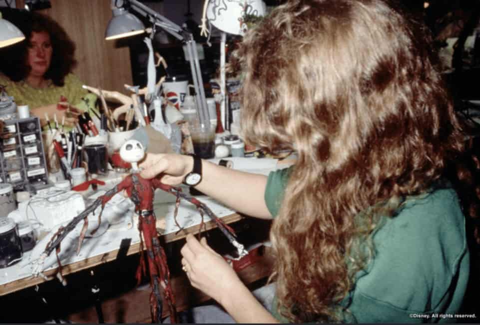 An artist in the workshop carefully works on the details of the Jack Skellington puppet in his famous pajamas.