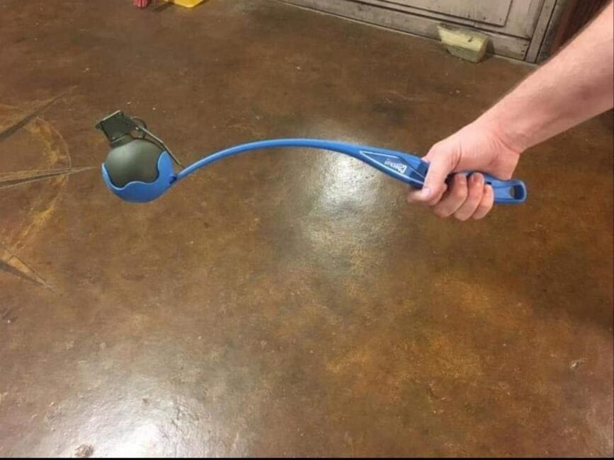 A funny perfect fit picture showing a grenade sitting inside a dog ball thrower like it belongs there.