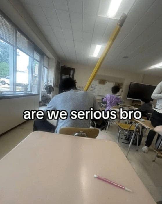 A funny classroom photo from a TikTok video of a student who has brought a giant, oversized novelty pencil to school.