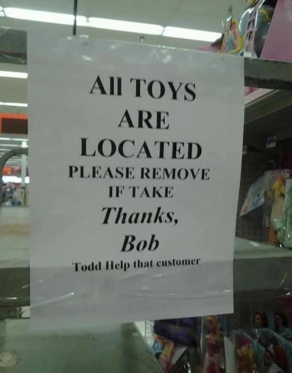 Printed store sign with mismatched lines: “ALL TOYS ARE LOCATED… PLEASE REMOVE IF TAKE… Thanks, Bob… Todd Help that customer.”