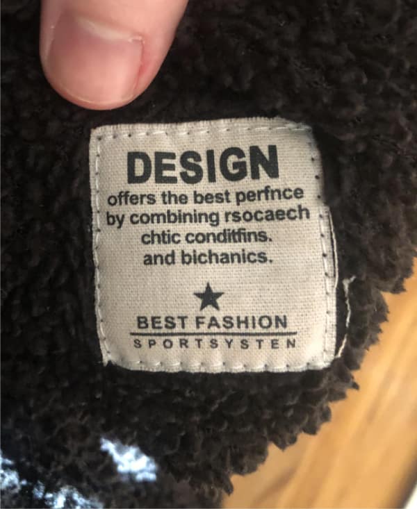 Clothing label reads “DESIGN offers the best perfnce by combining rsocaech, chtic condifns, and bichanics. BEST FASHION SPORTSYSTEM.”