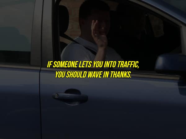 A driver giving the thank-you wave, illustrating an essential unwritten rule of the road for drivers.