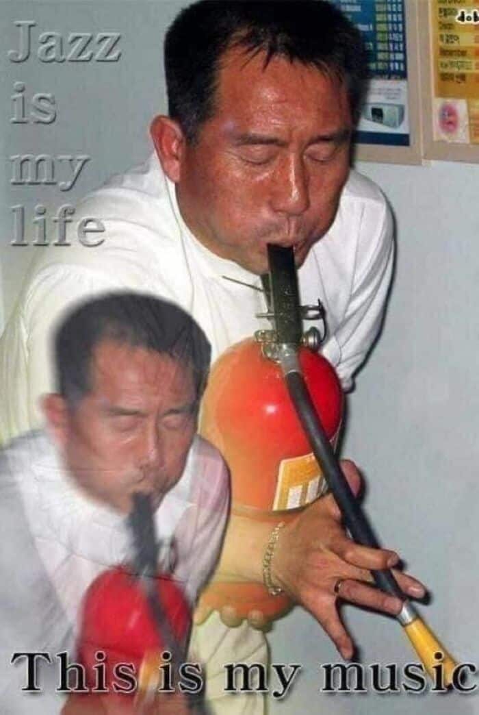 A weird photo with no context of a man passionately playing a fire extinguisher like a saxophone.