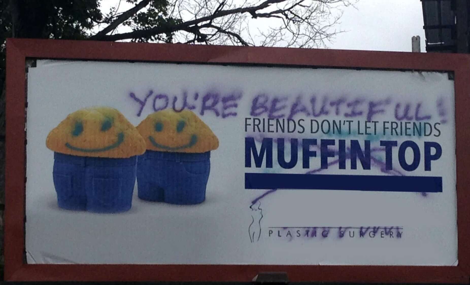 Wholesome vandalism on a plastic surgery ad where someone has spray-painted "You're beautiful!" over it.