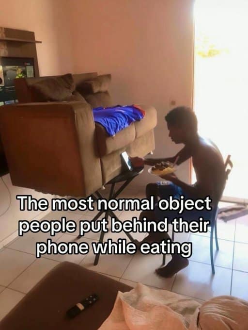 A funny TikTok meme exaggerating how people will use any object, including a giant couch, to prop up their phone while eating.
