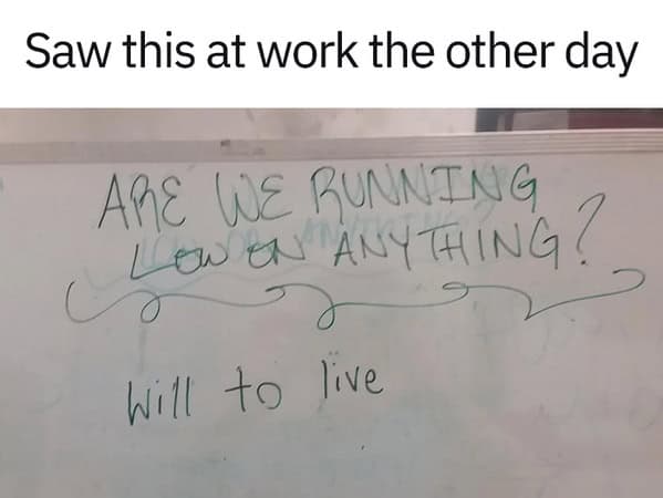 Whiteboard at work asks “Are we running low on anything?”; someone writes “will to live.” Work meme.