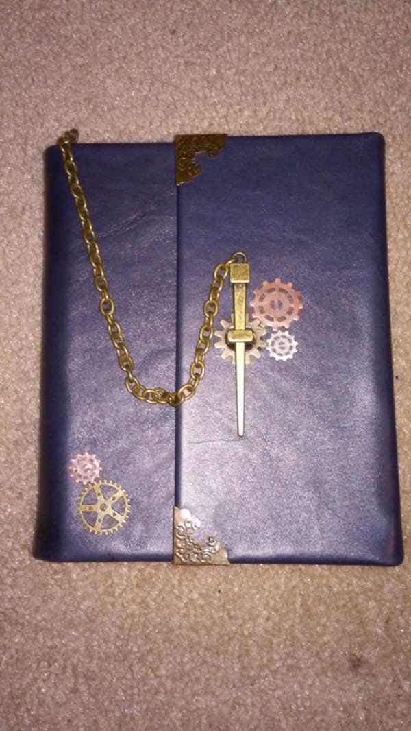A custom-decorated steampunk journal with brass gears and a chain, a fantastic DIY win for crafters.