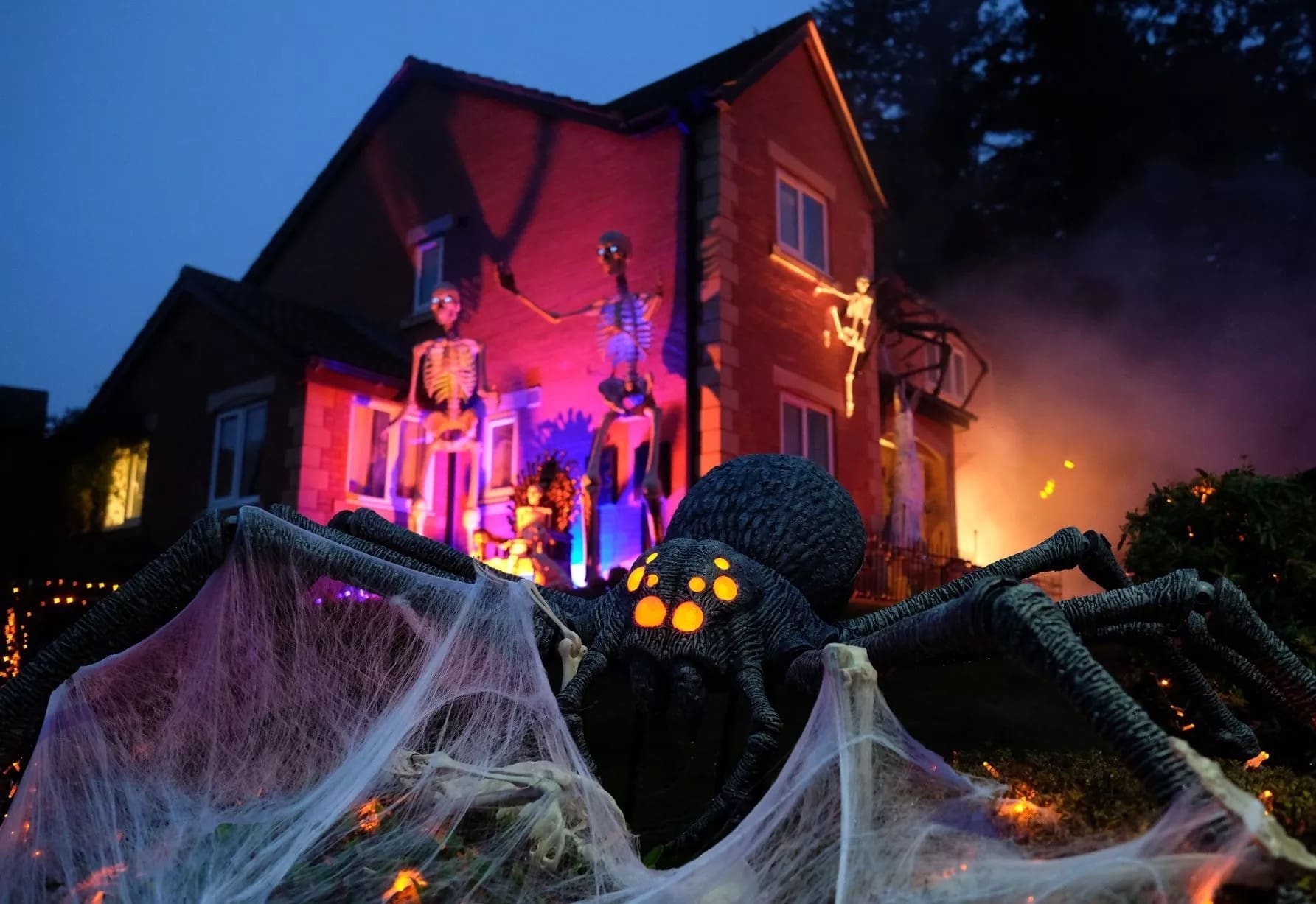 This amazing halloween house features a giant spider, glowing webs, and skeletons climbing the walls