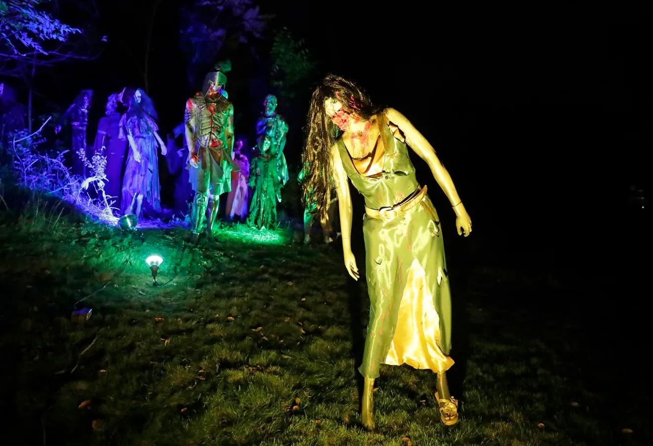 A terrifying amazing halloween house display featuring a horde of realistic zombie mannequins in a yard.