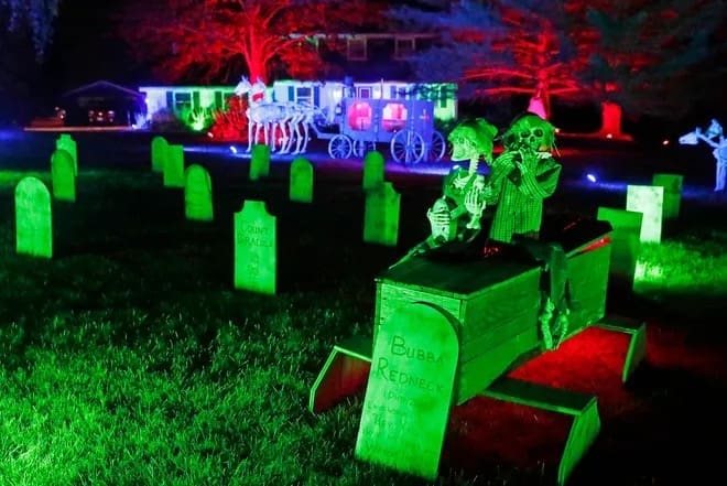 An amazing halloween house lawn decorated as a graveyard with a skeleton horse-drawn carriage