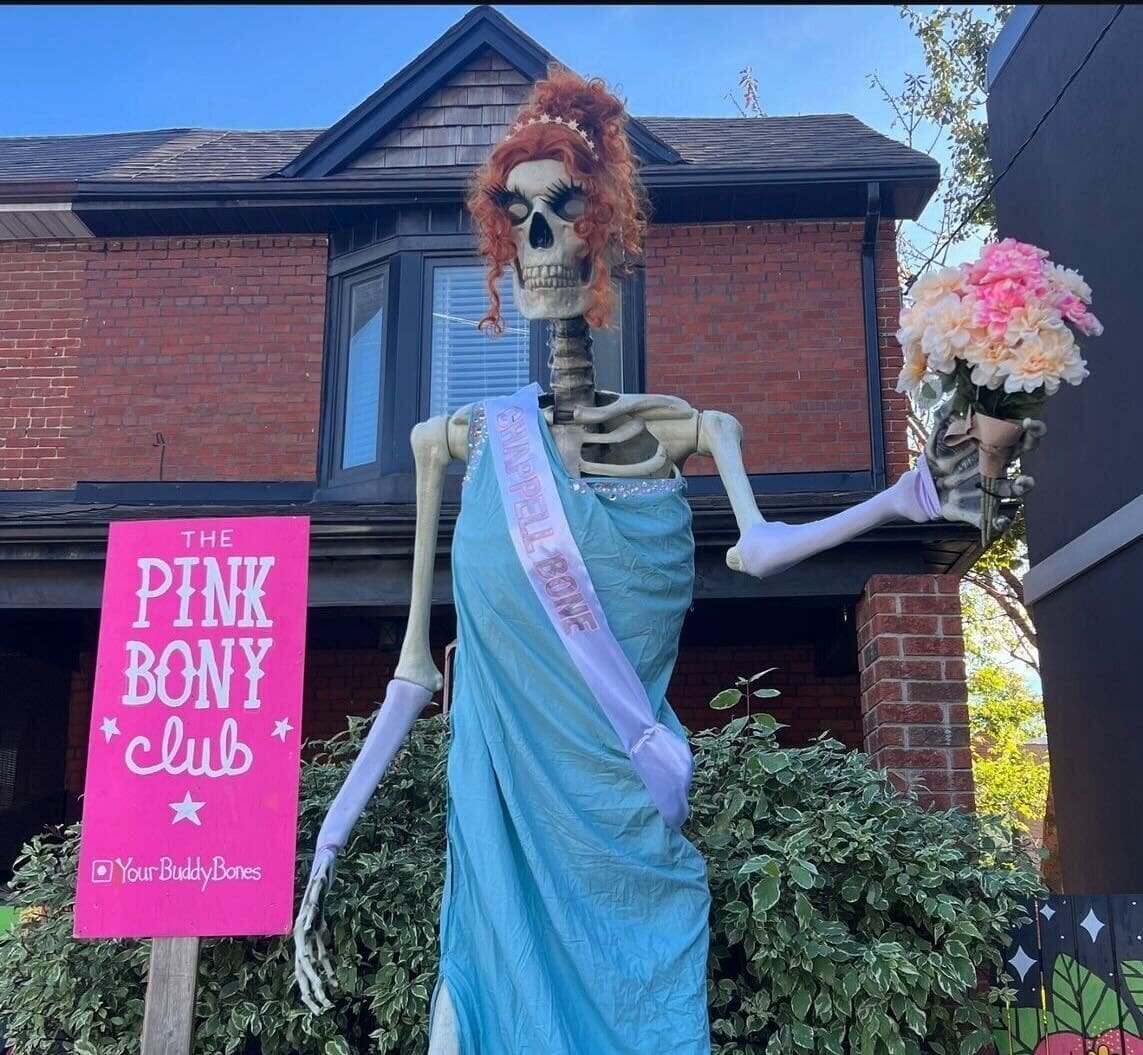 A funny amazing halloween house decoration showing a skeleton in a prom dress, wig, and sash.