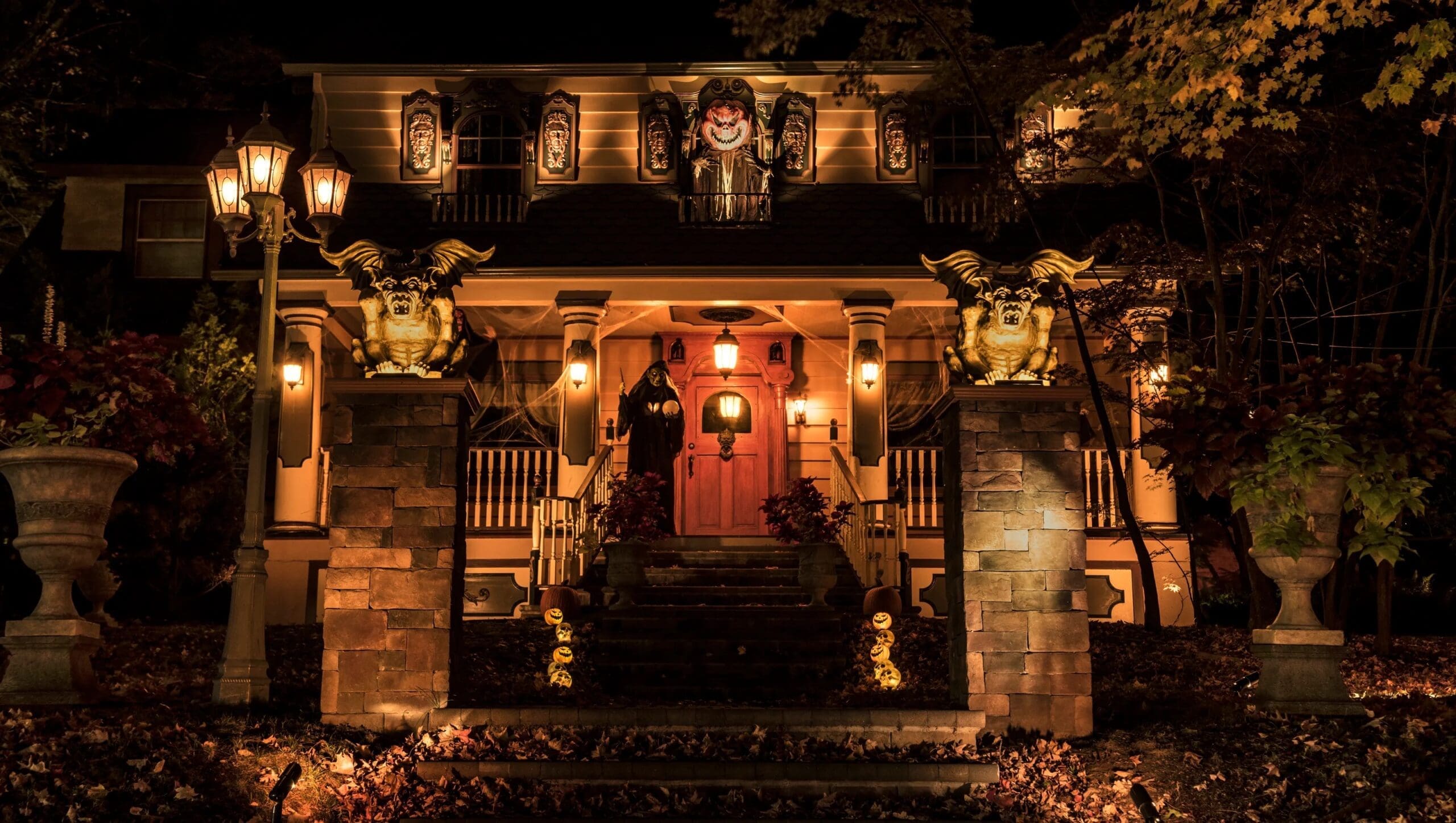 An elegant and amazing halloween house decorated like a classic haunted mansion with gargoyles and a reaper