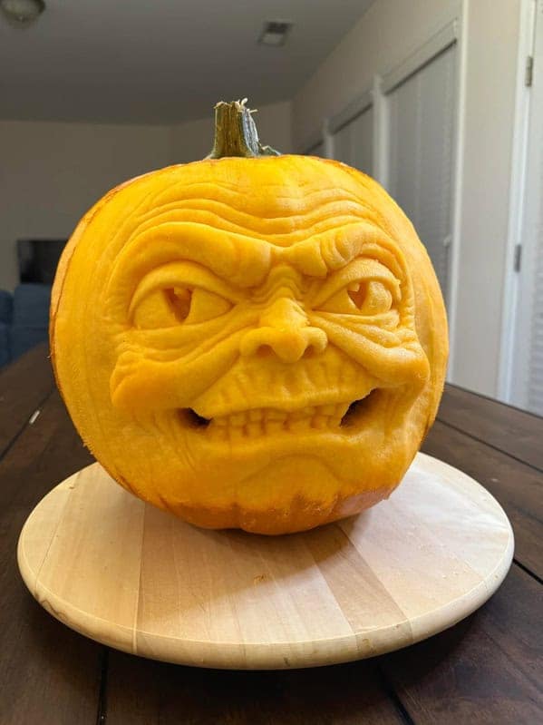 An amazing pumpkin carving featuring a highly detailed, three-dimensional sculpture of a menacing monster face