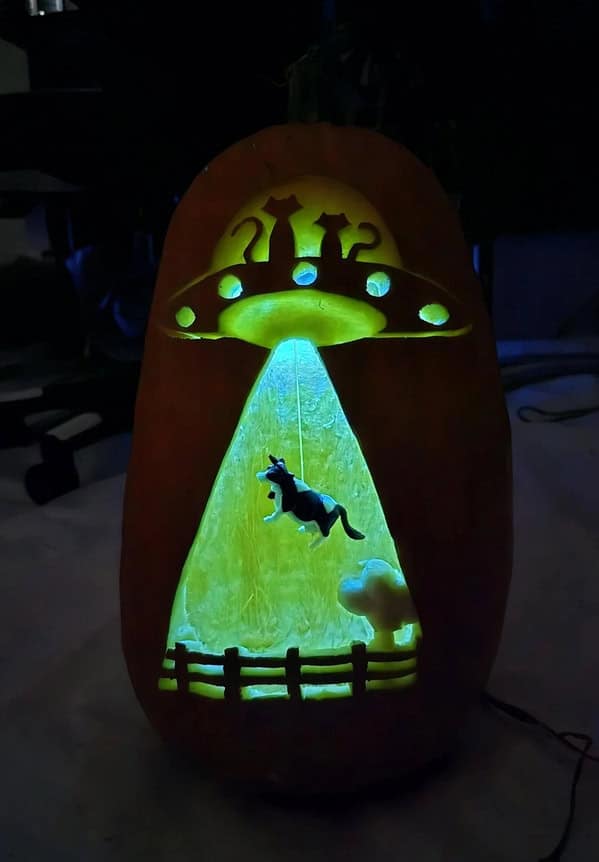 An amazing pumpkin carving diorama showing a UFO beaming up a cat with creative lighting effects