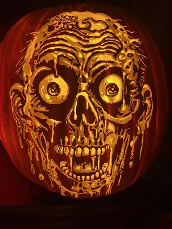 An amazing pumpkin carving with an incredibly detailed and gruesome zombie face lit from within