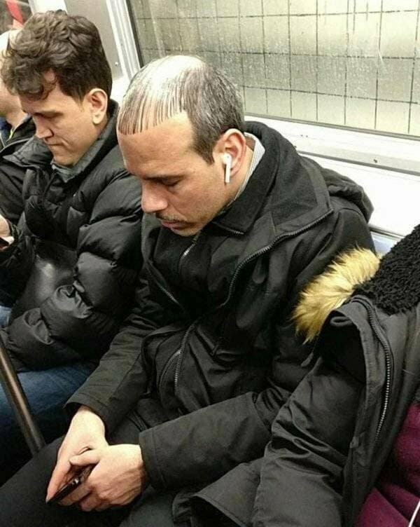 A man on a subway with one of the worst bad haircuts, a combover with bleached bangs.