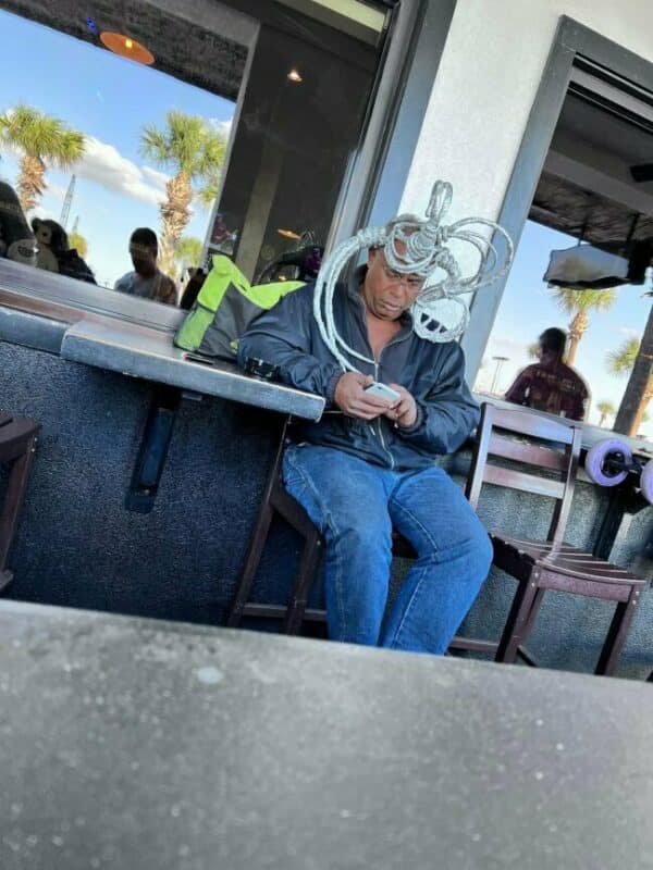 A bizarre example of bad haircuts featuring a man with his hair styled into a complex wire-like sculpture.